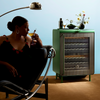 Woman sipping a cocktail next to a fully stocked closed Green Rocco.