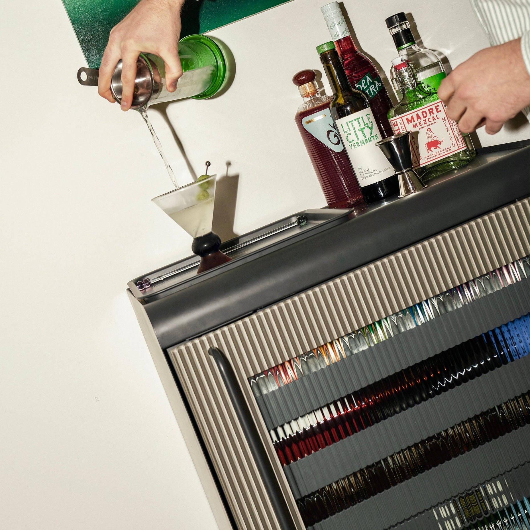 Person pouring drink from a shaker on the bar tray on top of a Graphite Rocco Fridge.